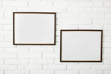 Empty posters hanging on white brick wall