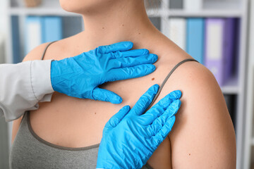 Doctor examining mole of young woman in clinic, closeup