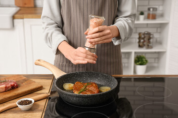 Woman frying tasty steak in kitchen