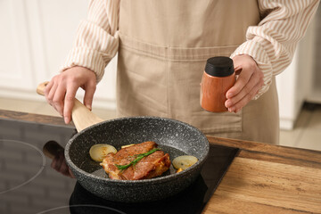 Woman frying tasty steak in kitchen