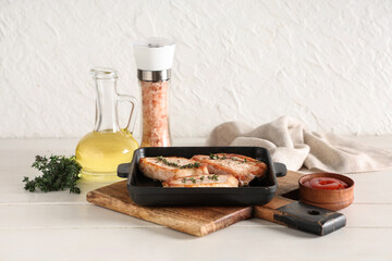 Frying pan with roasted steaks on white wooden table