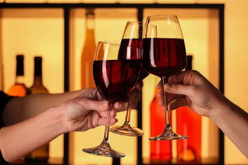 Hands of women clinking glasses of red wine in bar