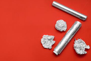 Aluminium foil rolls with crumpled sheets on red background