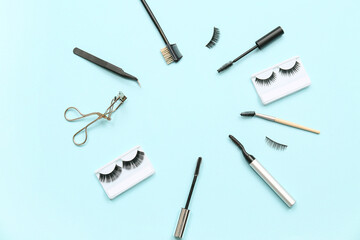 Frame made of different false eyelashes with tools on blue background