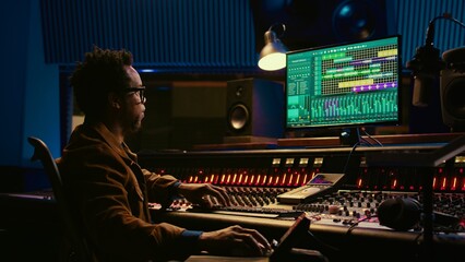 African american sound designer working with editing software to produce new tracks. Audio engineer...