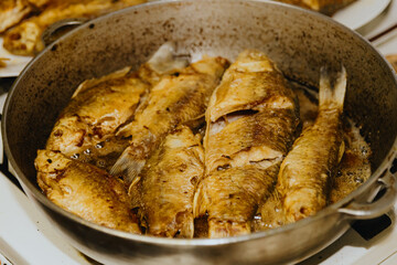 The fish is fried in a cast iron frying pan on the stove.