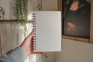 Hand holding blank sketchbook, mockup, business, notes, boho style, plants, artwork
