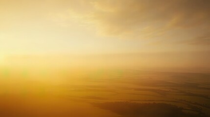 Obraz premium Golden, hazy sunrise or sunset over a landscape. Soft, warm light fills the sky and features a hazy view of land below.