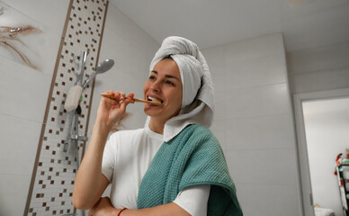 A woman with a towel wrapped around her head and a second towel draped over her shoulder is...