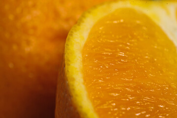 Macro view of a cut fresh orange, with whole orange as background. Showing detailed of juicy inside...