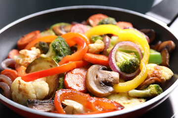 Frying pan with mix of vegetables and mushrooms on cooktop, closeup