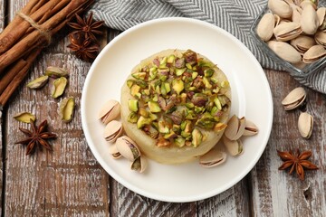 Delicious sweet semolina halva with pistachios and spices on wooden table, flat lay