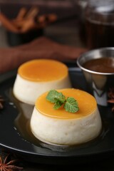 Tasty puddings with caramel sauce served on wooden table, closeup