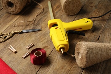 Hot glue gun and handicraft materials on wooden table