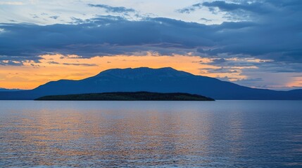 Serene sunset over calm waters reflecting vibrant colors with distant mountains and clouds