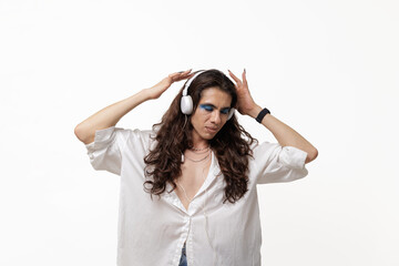 Fototapeta premium Non-binary person, male, in editorial pose, wearing headphones and dancing on white background for web and copy space for desing