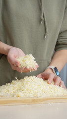 Grated cheese falls out of the cook's hand. Grated cheese for pizza.