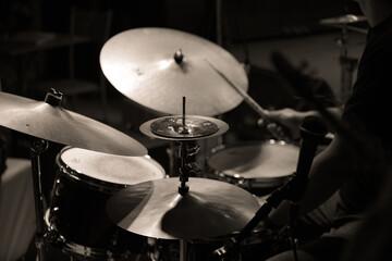  Black and white image of a drummer playing during a jazz concert, focusing on the cymbals and drumsticks.