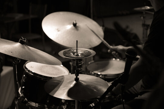  Black and white image of a drummer playing during a jazz concert, focusing on the cymbals and drumsticks. - Powered by Adobe