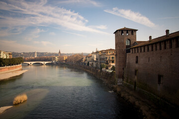 Obraz premium Adige River flowing through Verona, Italy, with historic buildings along the banks.