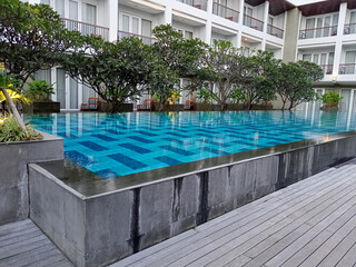 Modern Hotel Pool With Gray Stone Patio And Lush Green Landscaping