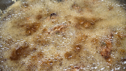 Cooking meat in bubbling sauce on a stovetop in a kitchen