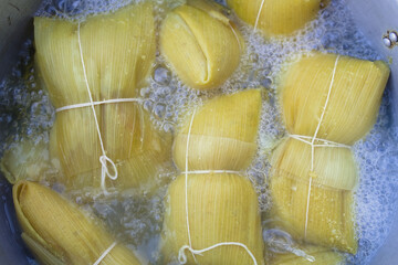 Photographs of a person preparing humitas using choclos, corn on the cob and a person eating humitas in a house in Chile