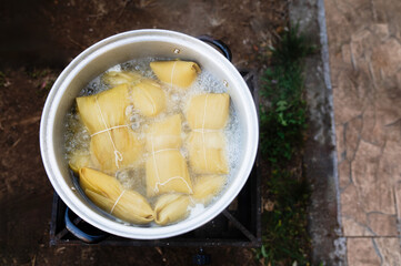 Photographs of a person preparing humitas using choclos, corn on the cob and a person eating humitas in a house in Chile