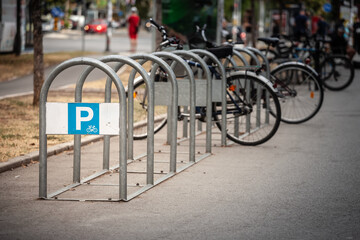 Fototapeta premium Selective blur on a A designated bicycle parking area with sturdy metal racks on a busy sidewalk. A clear “P” sign indicates where cyclists can secure their bikes.