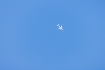 雲のない快晴の青空を飛ぶ白い機体の飛行機
