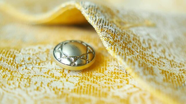 Elegant button on intricate yellow fabric at close range
