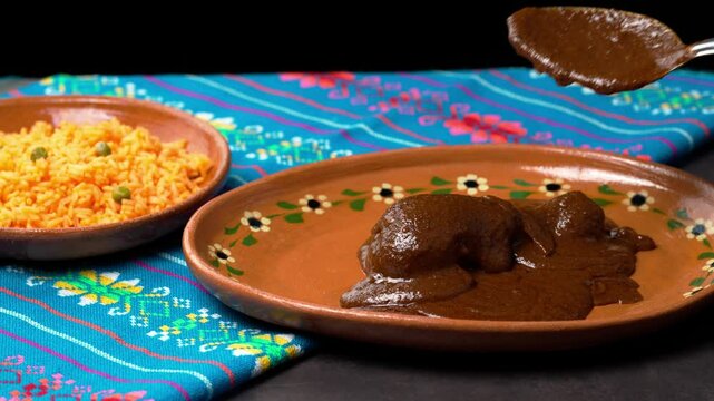 Serving mole poblano sauce on a clay plate with a piece of chicken, food from mexico