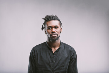 Obraz premium Serious young man with dreadlocks posing on plain background