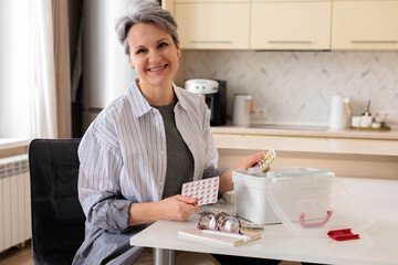 Beautiful, well-groomed and aged woman pensioner aged with gray hairchecking medicines 