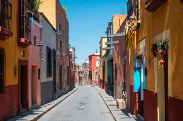 Fototapeta premium Colorful Colonial Street and Road of San Miguel de Allende Mexico. Mexican streets with colorful houses of all colors in the sunshine