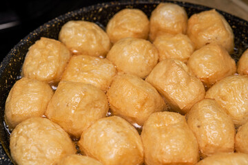 A chef is frying tofu in a pan in the kitchen