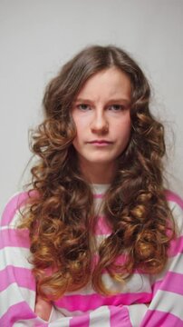 Vertical video little curly-haired girl showing displeased expression