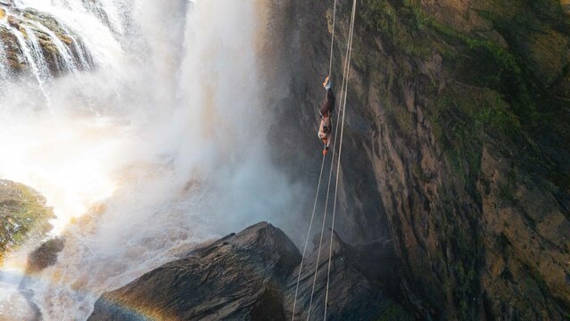 Woman abseiling upside down in front of a waterfall in Minas Gerais