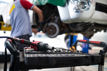 Obraz premium Mechanic's Tools: A close-up shot of an air-powered impact wrench and socket set rests on a workbench, reflecting the hard work and precision of a skilled mechanic.