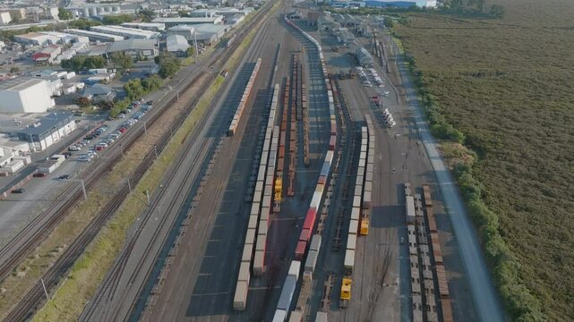 Aerial view of a busy rail yard. Freight cars and containers are parked along multiple tracks. Industrial buildings and city are visible in the background. PENROSE, AUCKLAND, NZ