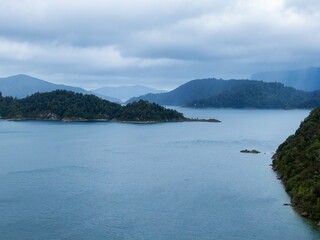 Misty Lake Waikaremoana scene with forested islands and mountains. Tranquil water reflects the...
