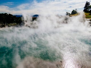 Steaming hot spring, geothermal activity, New Zealand. Thick vapor rising from turquoise water....