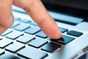 Finger of the computer user, he presses the delete button on the computer keyboard	