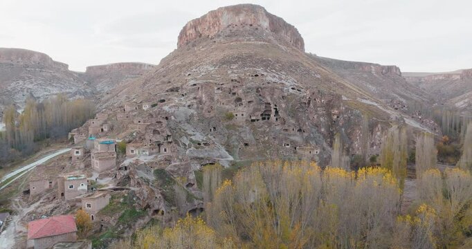 Drone approaches historical rock settlements in Soğanlı Valley. Cave houses, abandoned old stone structures and natural volcanic formations bear traces of the region's ancient past.