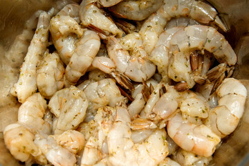 marinated raw shrimp.Stainless steel bowl full of shrimp have visible spices, ready to cook.Close up