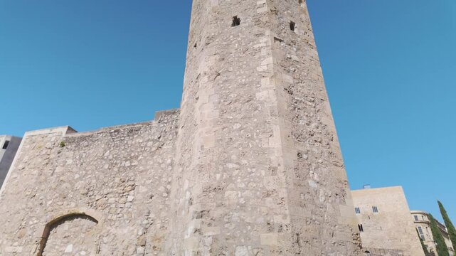 Low angle view of Monges Tower, part of Tarragona's ancient city walls, showcasing historical architecture against a clear blue sky