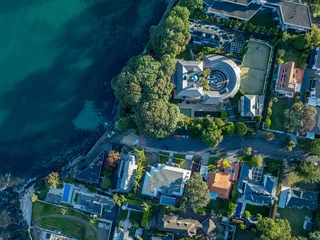 High-angle view of luxurious waterfront homes. Coastal properties with manicured gardens, pools, and tennis courts. A beautiful residential neighborhood. TAKAPUNA, AUCKLAND, NZ
