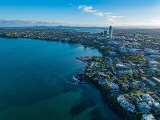 Fototapeta premium Aerial view of Auckland, New Zealand, showcasing coastal residential areas and the city skyline. Coastal homes and city buildings are visible. TAKAPUNA, AUCKLAND, NZ