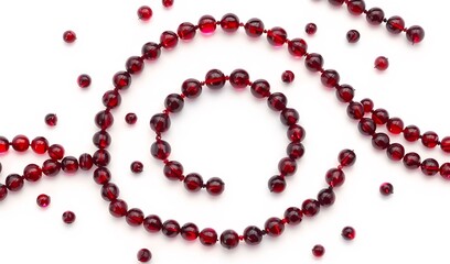 Obraz premium Elegant ruby beads swirl softly against white background creating a luxurious mood. AI Generated