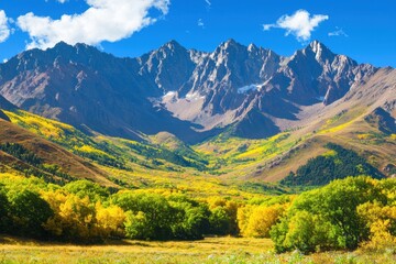 Naklejka premium A stunning landscape featuring majestic mountains, vibrant green and yellow foliage, and a clear blue sky, showcasing nature's beauty.